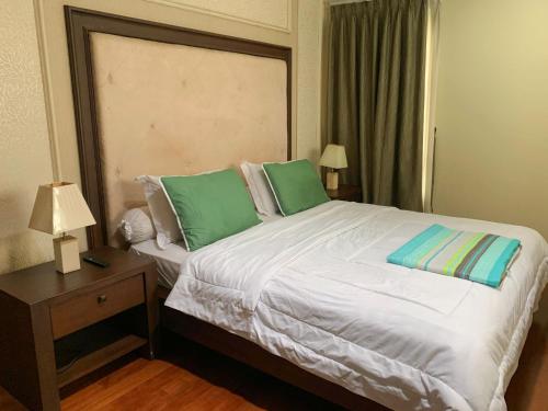 a bedroom with a large bed with green pillows at Trivana Pool View 3BR Senayan in Jakarta