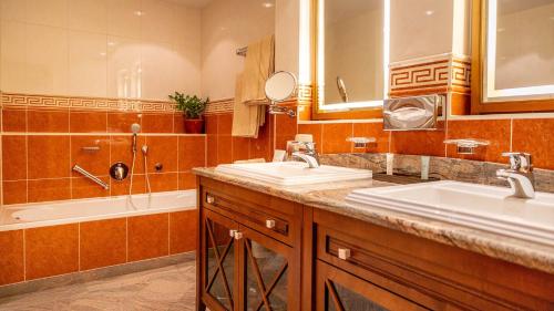 a bathroom with two sinks and a bath tub at Altstadthotel Bräuwirt in Weiden