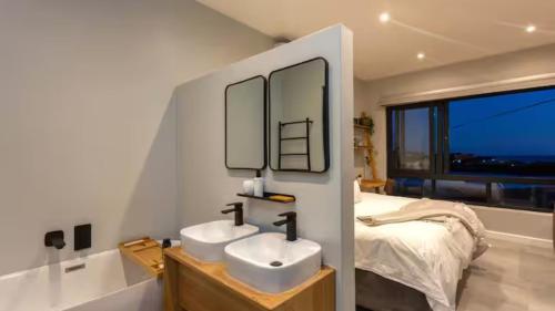 a bathroom with two sinks and a bed with a window at Blue Bay Studio Apartment in Wilderness