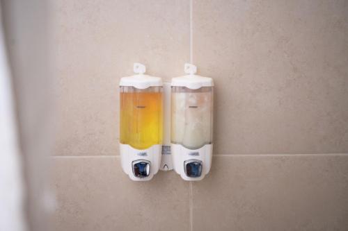 two soap dispensers are hanging on a wall at Trivana Pool View 3BR Senayan in Jakarta