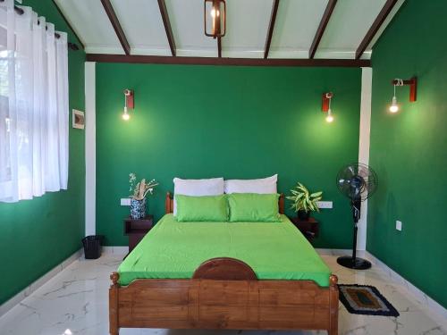 a green bedroom with a bed with a green wall at Fair view in Induruwa