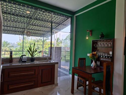 a kitchen with a table and a green wall at Fair view in Induruwa