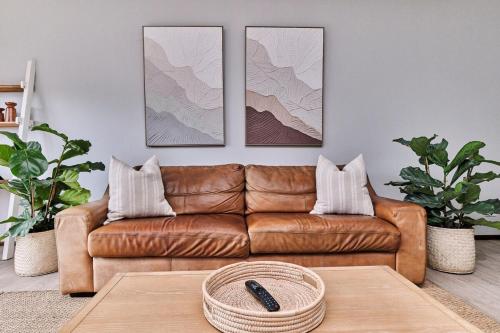 a brown leather couch in a living room with three pictures at Afrikaya Luxurious Apartment in Roodepoort