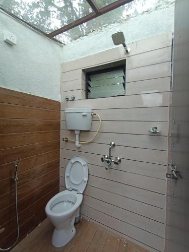 a bathroom with a toilet and a window at teak trail in Pune