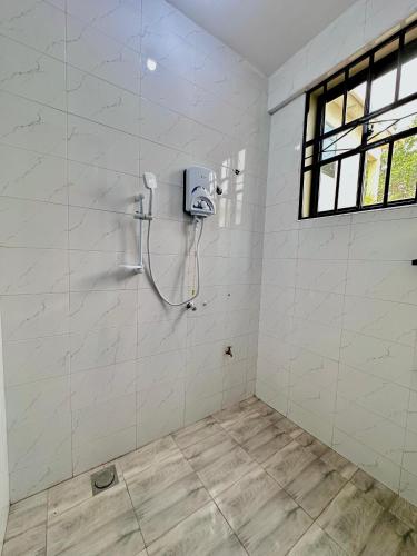 a bathroom with a shower in a white wall at Mbogo Safari Hotel in Karatu