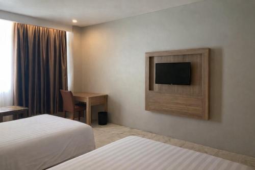 a hotel room with two beds and a flat screen tv at Manna Hotel Pematangsiantar in Pematangsiantar