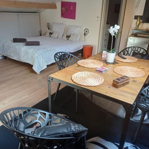 a room with a table and chairs and a bed at Les Jasmins de Salelles in Le Bosc
