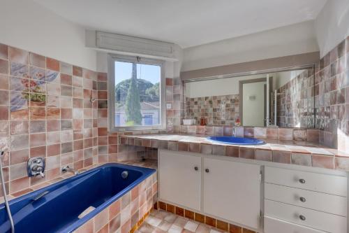 a bathroom with a blue tub and a window at Maison Gecko - Proche de la plage in Cavalaire-sur-Mer