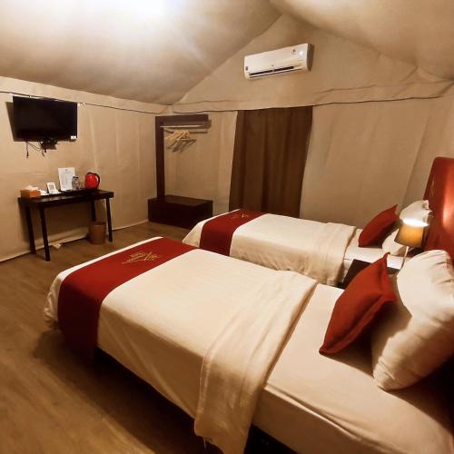 a hotel room with two beds and a television at "D'BAMBOO KAMP" Desa Wisata Ekang in Lagoi