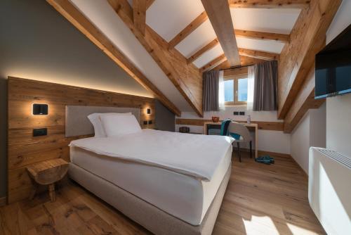 a bedroom with a large white bed and wooden walls at Green Hotel Genzianella in Roncone