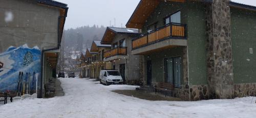 a snow covered street next to a building with a van at Greenfield Bakuriani, Mountain Villas & Homes in Bakuriani