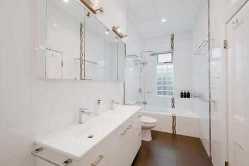 a white bathroom with a sink and a toilet at Ironbark Oasis - Serene Poolside Haven by Mudgee CBD in Mudgee