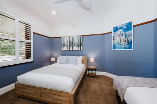 a blue bedroom with two beds and a window at Ironbark Oasis - Serene Poolside Haven by Mudgee CBD in Mudgee