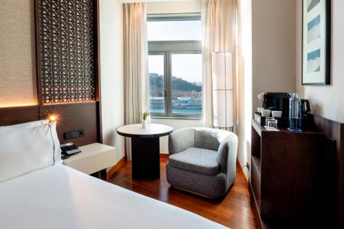 a hotel room with a bed and a chair and a window at Eurostars Grand Marina Hotel GL in Barcelona