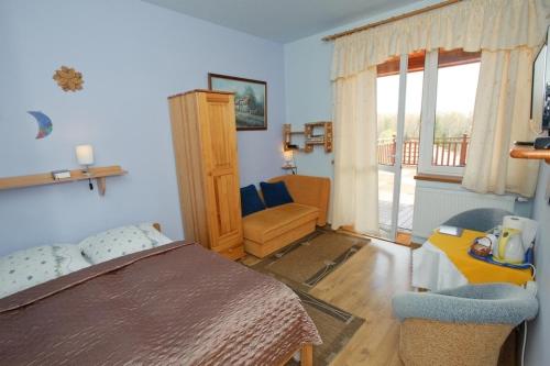 a bedroom with a bed and a chair and a window at Dom Gościnny Barbara in Polańczyk