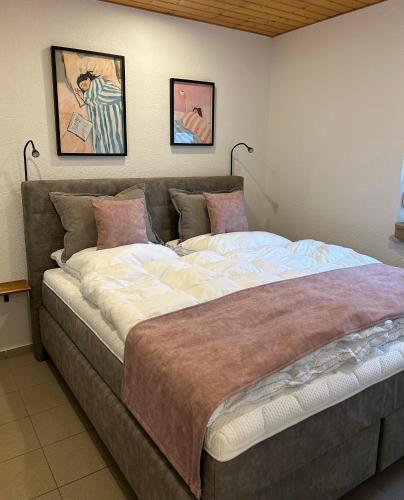 a large bed in a bedroom with two pictures on the wall at ZweiundMeer Bungalow 2 in Wiek auf Rügen