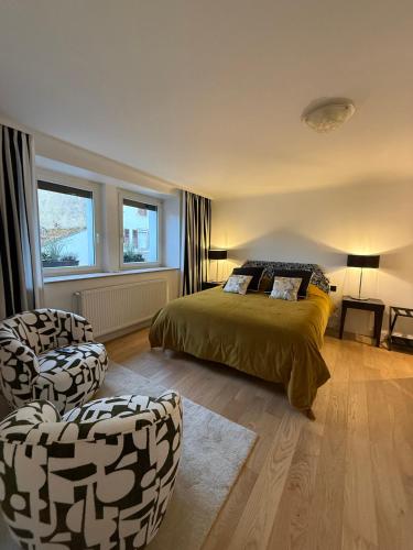a bedroom with a bed and two chairs at La Maison Dehlinger, chambres hôtelières et gîte in Gros-Réderching