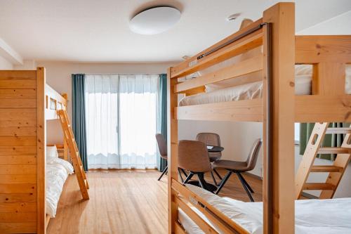 a room with bunk beds and a table and chairs at ライズ201 in Kasugai