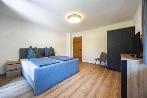 a bedroom with a large blue bed and a desk at Schusterhäusl in Rauris