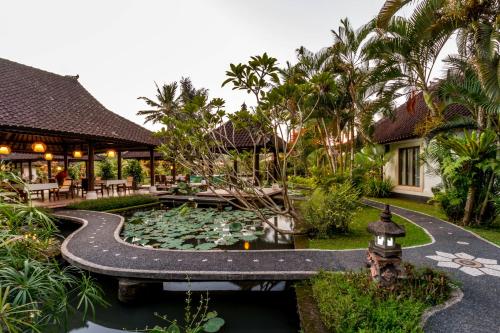 a garden with a pond and a house at Villa Taman di Blayu by AGATA in Tabanan