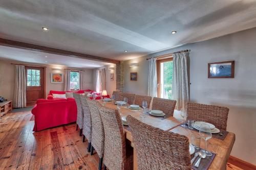 Chalet Heidi في شامونيه مون بلان: غرفة طعام بها طاولة طويلة وأريكة حمراء