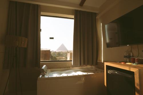 a bathroom with a tub with a view of the pyramid at Voyage On The Spot in Cairo