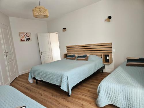 a bedroom with two beds and a wooden headboard at Gîte La Gloriette proche Futuroscope in Neuville-du-Poitou