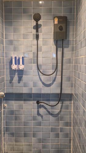 a tiled bathroom with a shower with a blow dryer at HOM's HOSTEL in Phuket