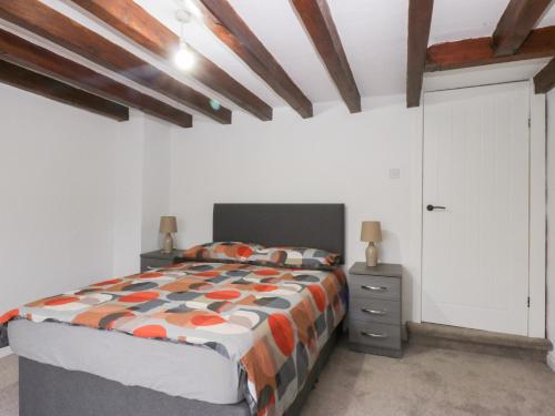 a bedroom with a bed and a white wall at Chandlers Cottage in Conwy