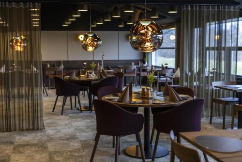 ein Restaurant mit Tischen, Stühlen und Lichtern in der Unterkunft Scandic Aalborg Øst in Aalborg