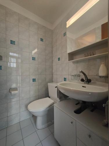 a white bathroom with a toilet and a sink at Garni Rosa Delle Alpi in Gordola