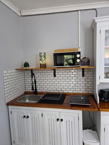 a kitchen counter with a sink and a microwave at Roux Casa 2 in Swellendam