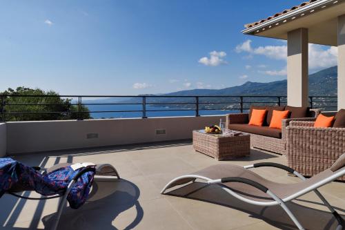 a patio with a couch and chairs on a balcony at Résidence & Hôtel Aria Marina in Propriano