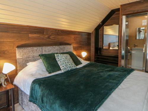 a bedroom with a large bed with a green blanket at Glamping Tri Pod 2 - Gower in Swansea