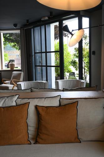 a living room with a table with pillows and windows at Otonali hôtel by Breizh Café in Saint Malo