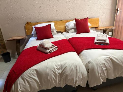 two beds with red and white blankets and towels on them at Witgatboom Boskamp in Naboomspruit