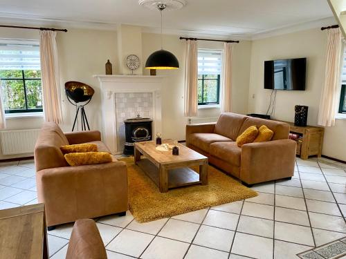 a living room with two couches and a fireplace at Buitenplaats 67 with optional sauna in Callantsoog