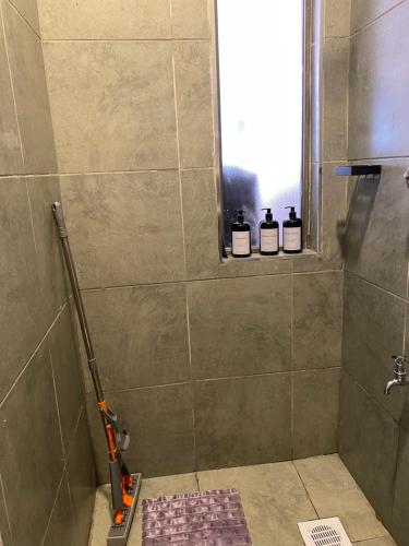 a bathroom with a shower with three bottles of soap at Nomads nest suites in Kiambu