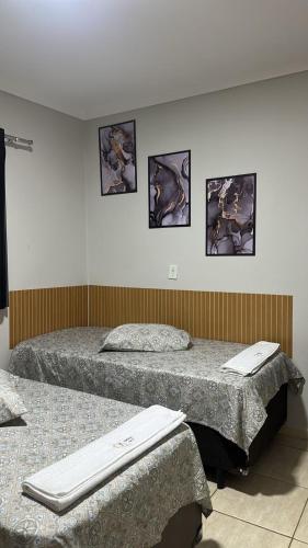 two beds in a room with pictures on the wall at Sobrado de luxo em condomínio in Araçatuba