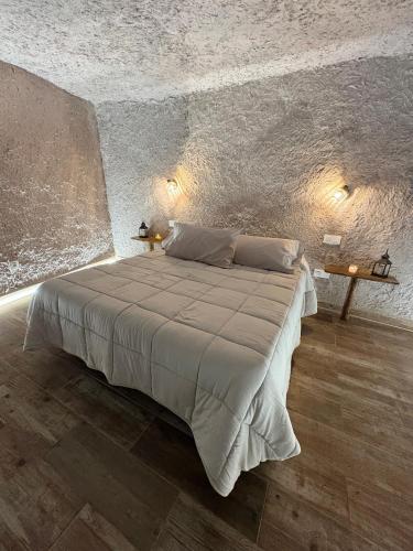 a bedroom with a large bed in a stone wall at El Refugio de Juncalillo in Gáldar