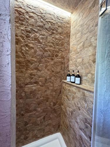 a bathroom with three bottles of wine on a stone wall at El Refugio de Juncalillo in Gáldar