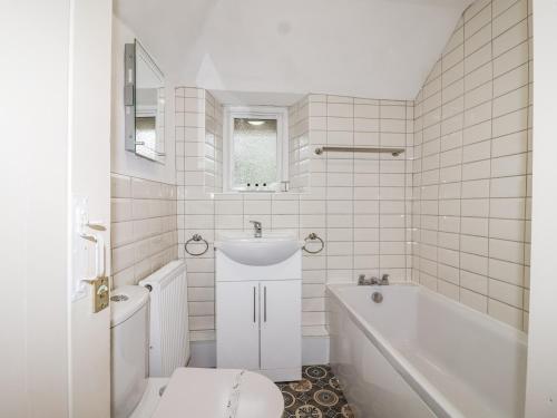 a white bathroom with a tub and a sink at Orchard Cottage in Dawlish