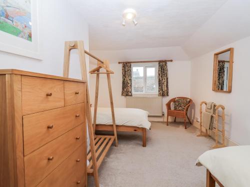 a bedroom with a dresser and a bed and a ladder at Orchard Cottage in Dawlish