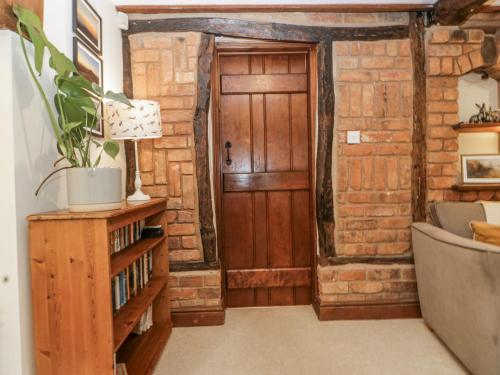 a room with a wooden door in a brick wall at Magpie Cottage in Worcester