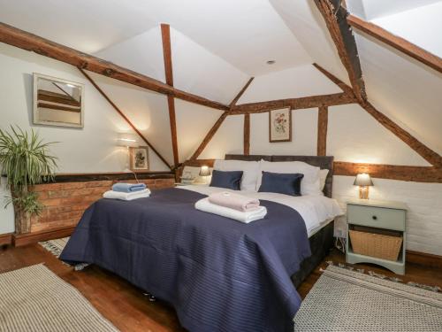 a bedroom with a large bed in a room with beams at Magpie Cottage in Worcester