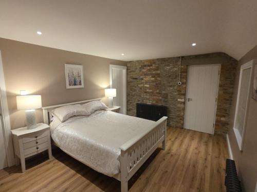 a bedroom with a white bed and a brick wall at Annies Farm Cottage in Derry Londonderry