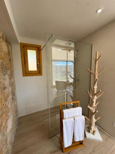 a bathroom with a glass shower and a chair with towels at Mas del Bot in Valderrobres