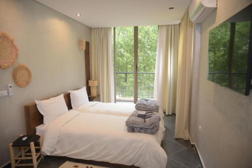 a hotel room with two beds and a window at La Perle Ourika Valley Guest House in Ourika