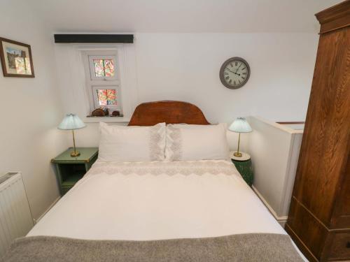 a bedroom with a bed and a clock on the wall at Tucked Away in Evesham