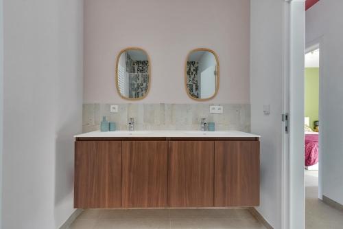a bathroom with a sink and two mirrors at 't Vennehuys - vakantiehuis nabij Bokrijk in Genk